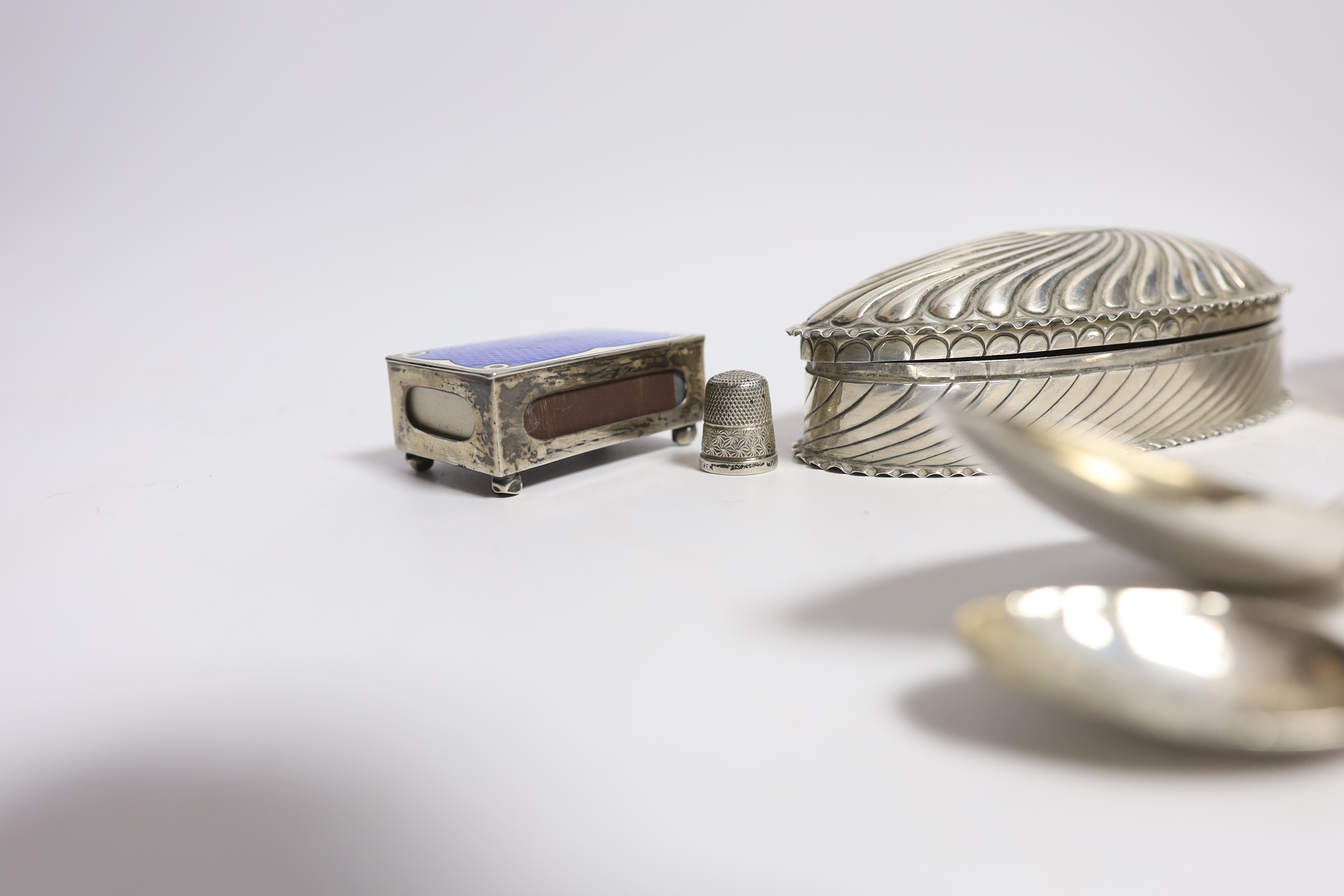 A late Victorian repousse silver oval trinket box by Horton & Allday, Birmingham, 1890, 15.2cm, together with five items of silver flatware, a silver bowl, silver and enamel matchbox sleeve and a sterling thimble.